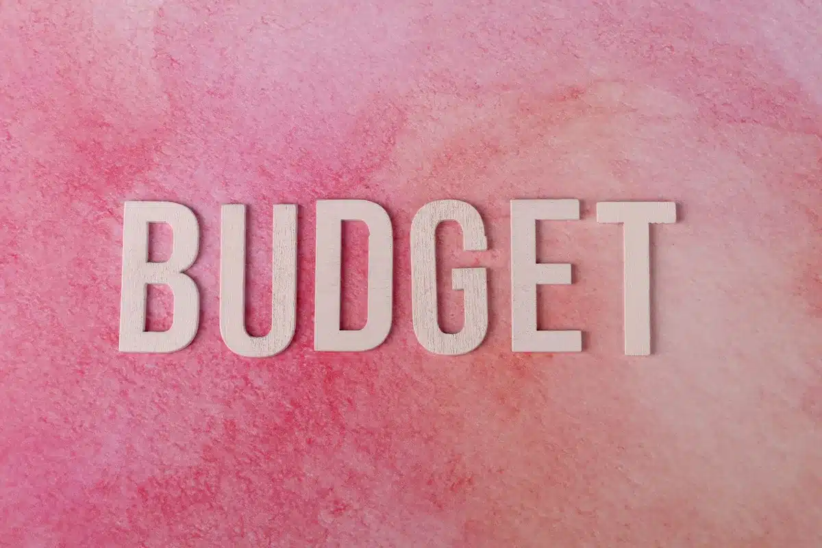 Cahier de budget ouvert avec stylo, pièces de monnaie et notes de travail financier