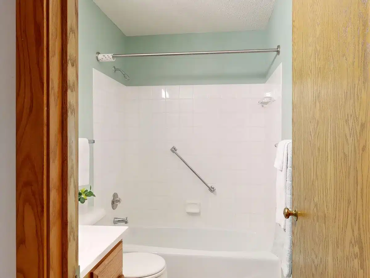 Salle de bain adaptée avec barres d'appui, revêtement antidérapant et douche accessible de plain-pied