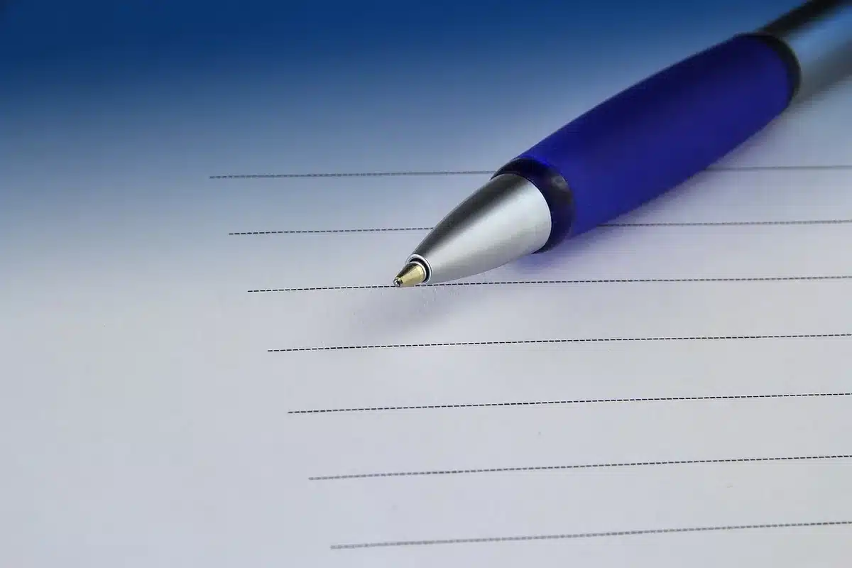 Carnet ouvert avec une liste d'intentions et un stylo sur une table ensoleillée
