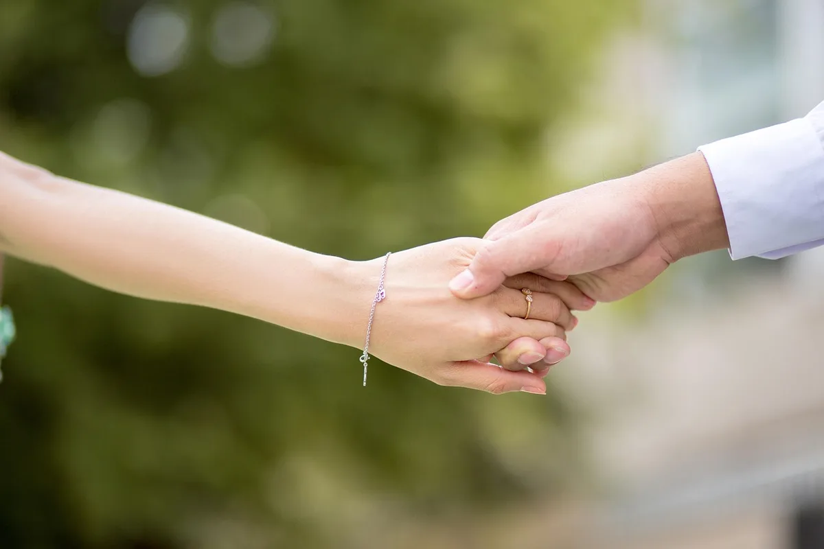 Couple se tenant la main, symbole de confiance et d'engagement mutuel.