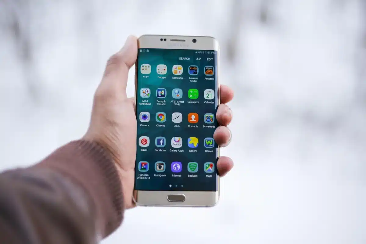 Personne tenant un smartphone avec une application de loterie et une copie de ticket