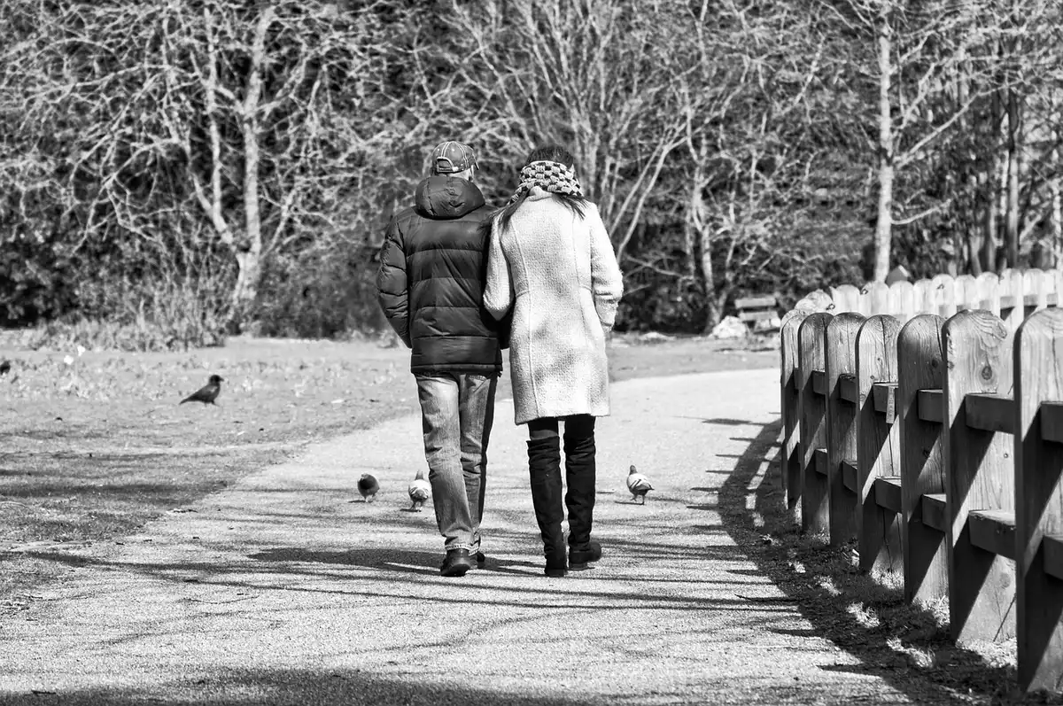 Couple marchant ensemble dans un parc en pleine journée, symbole d'actions concrètes partagées