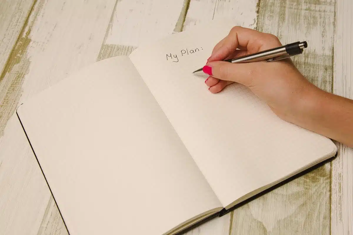 Personne anonyme écrivant dans un carnet pour noter des intentions de nouvelle lune