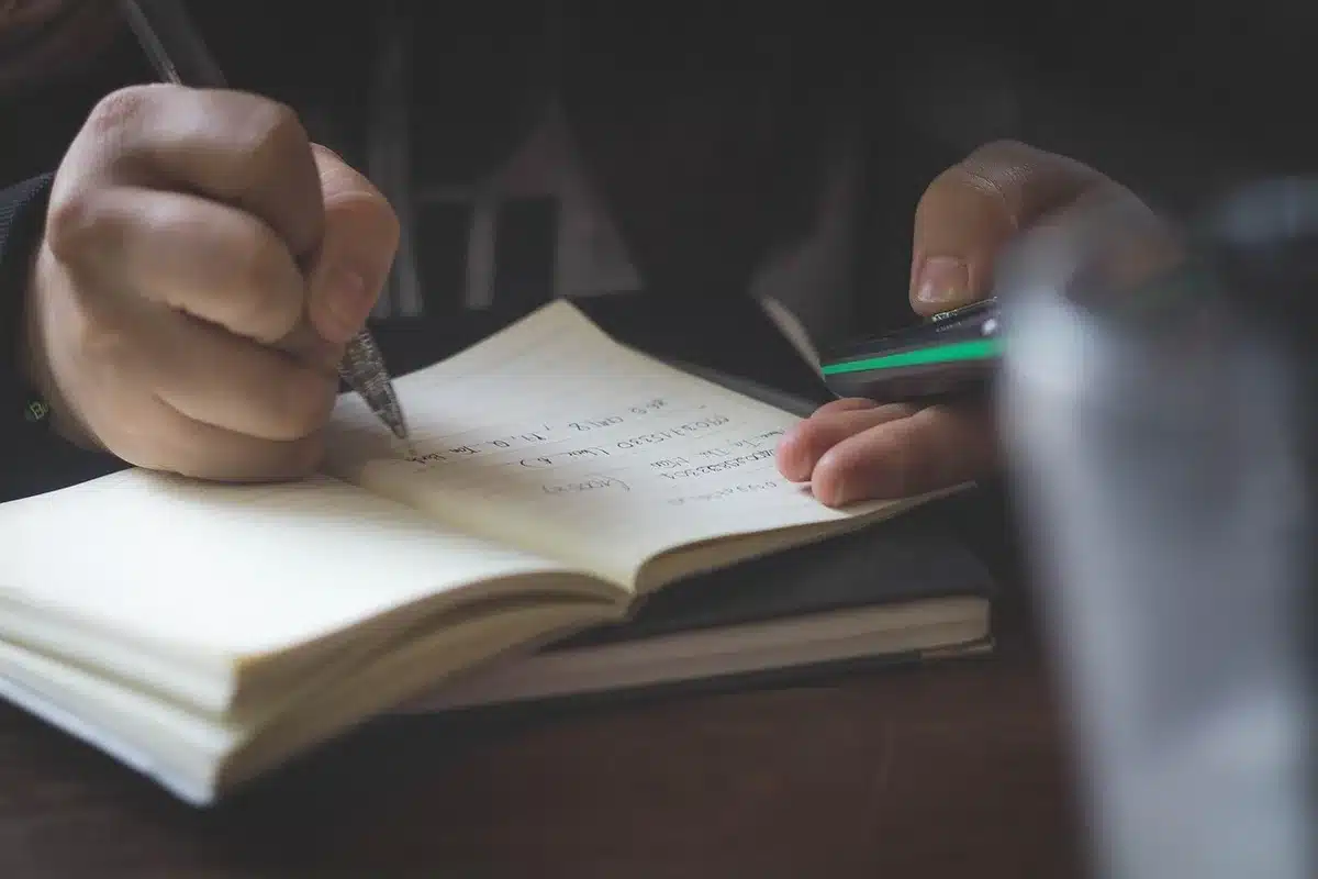 Personne écrivant des notes sur une relation près d'une fenêtre en plein jour