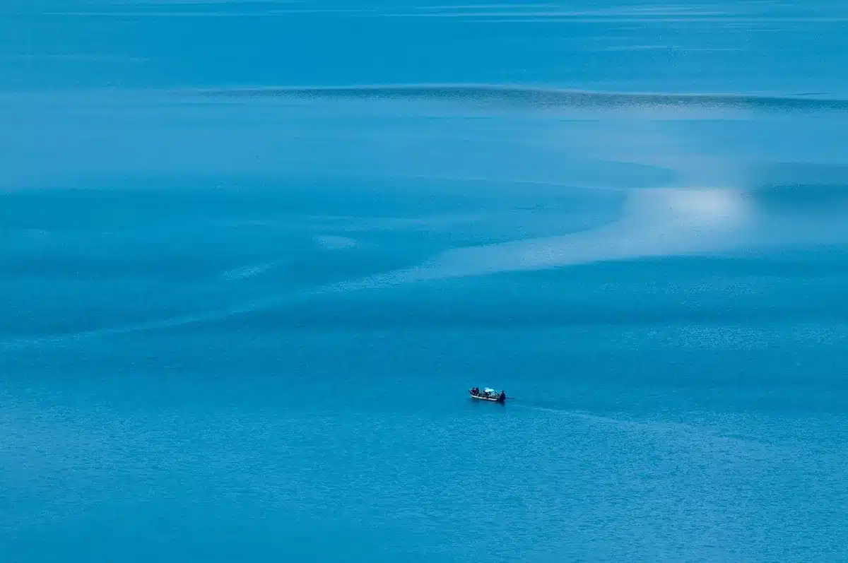 Main tenant un smartphone filmant une étendue d'eau depuis un petit bateau
